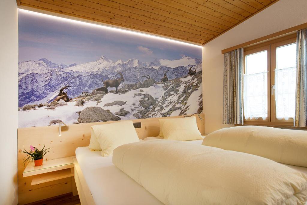 a bedroom with two beds and a painting on the wall at Hotel Alpsu in Disentis