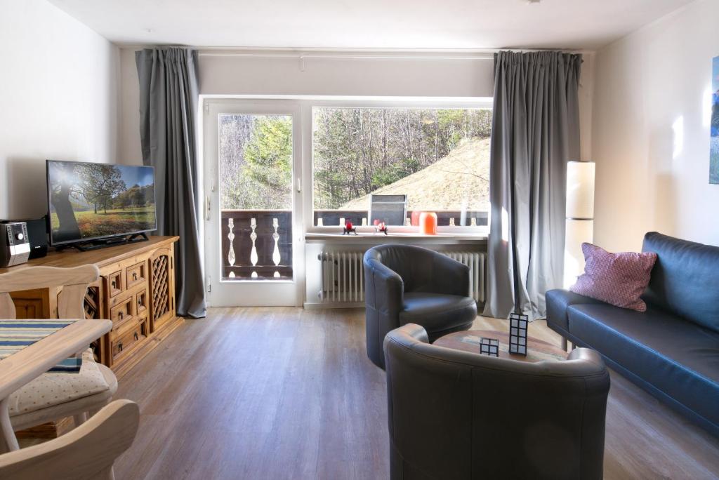 ein Wohnzimmer mit einem blauen Sofa und einem TV in der Unterkunft Malerblick - a73966 in Mittenwald