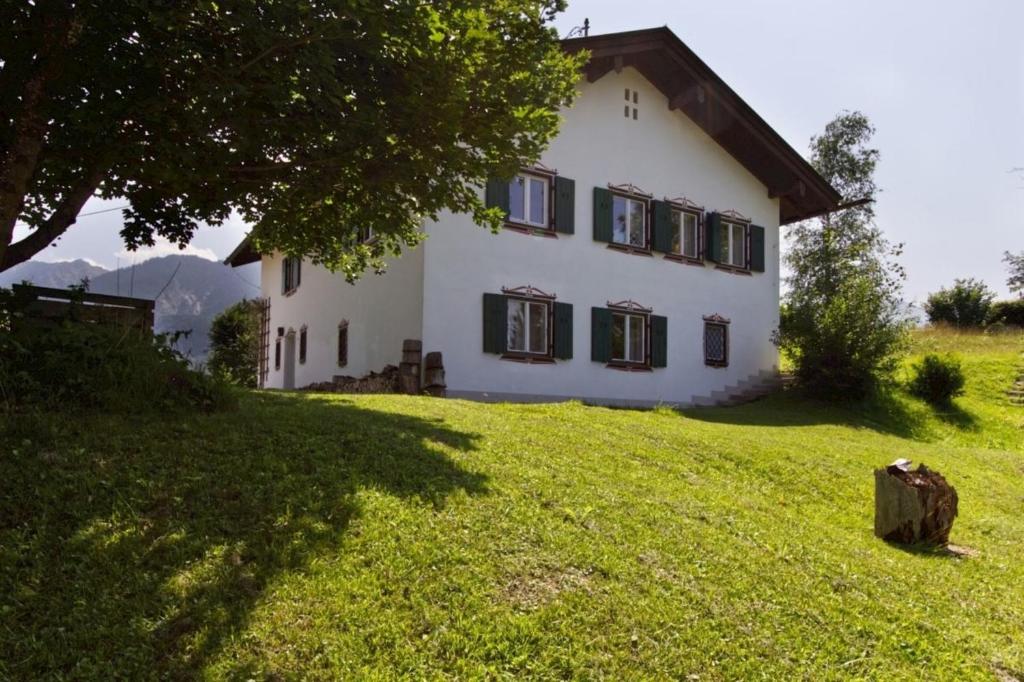 una grande casa bianca su una collina erbosa di Ferienhaus Alpenbichl - a74010 a Krün