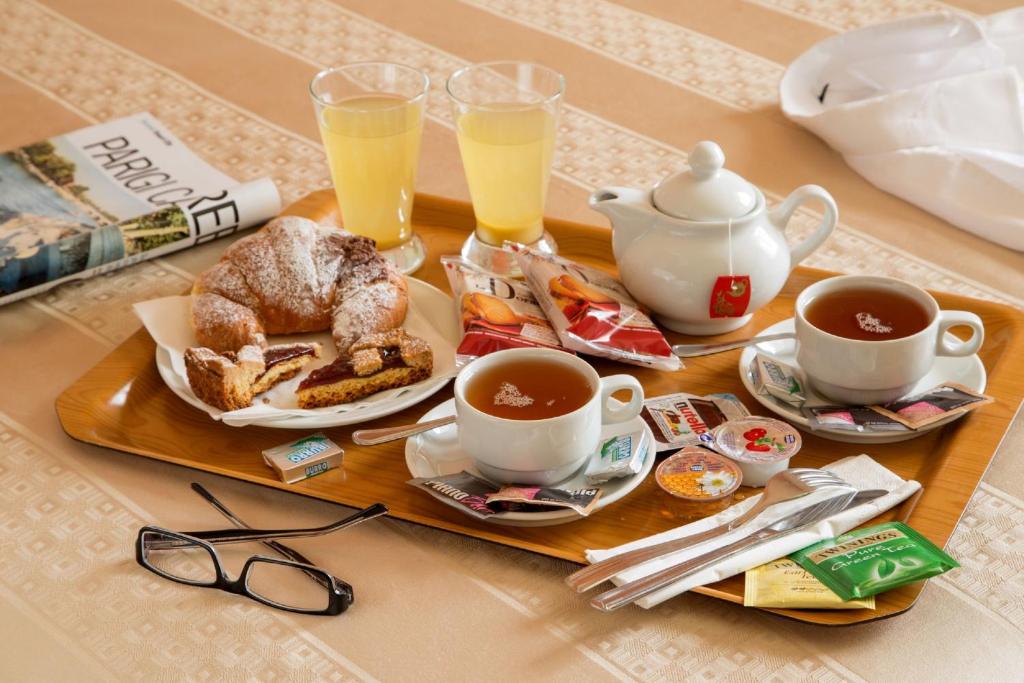a tray with two cups of coffee and a plate of food at Hotel Mediterraneo in Livorno