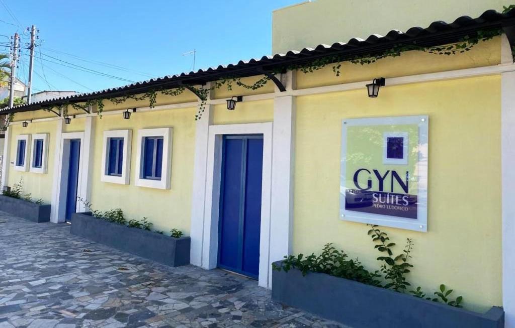 a yellow building with blue doors on a street at GYN SUITES - SUITES EM GOIÂNIA GO in Goiânia