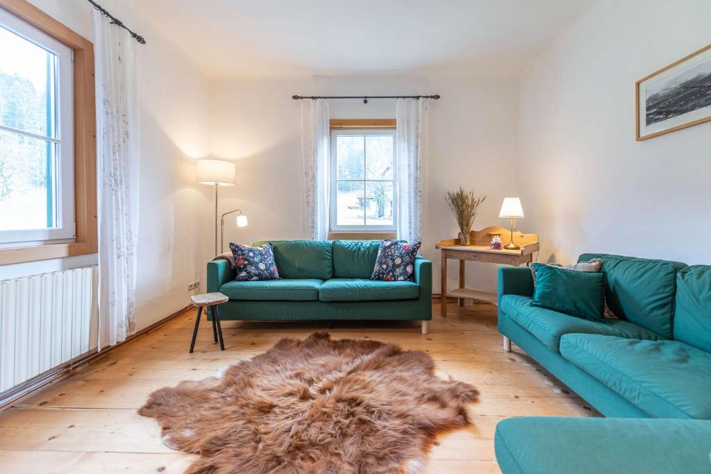 a living room with two blue couches and a rug at Das Haus in Altaussee in Altaussee