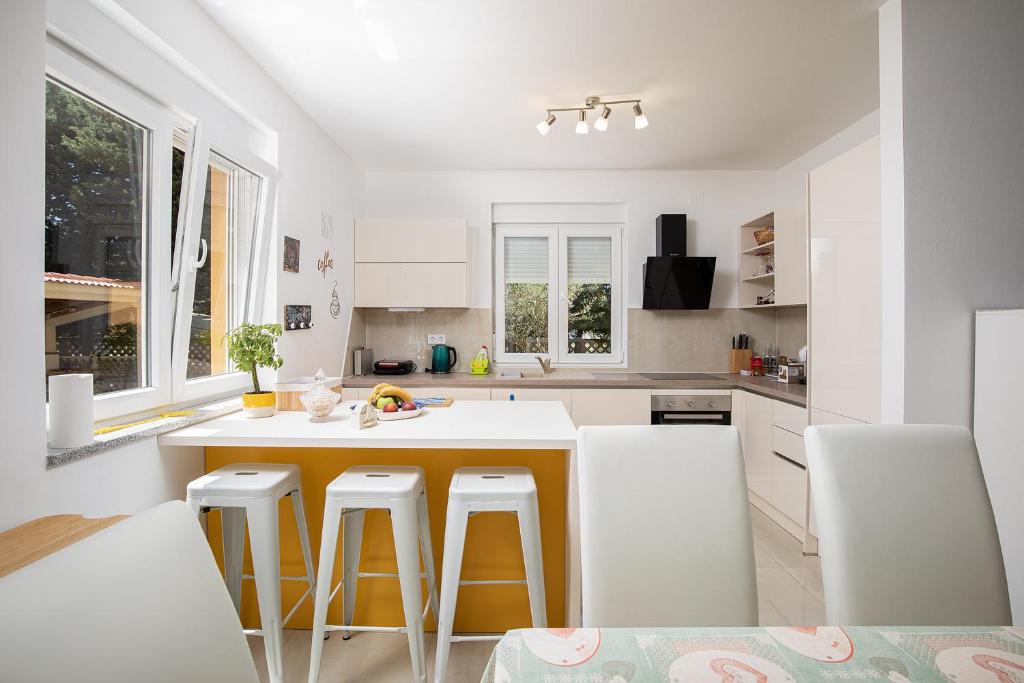 a kitchen with white cabinets and a yellow island with bar stools at Apartment J&E in Medulin