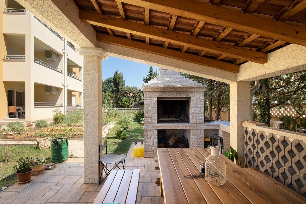 patio z kamiennym kominkiem i drewnianym stołem w obiekcie Apartment J&E w Medulinie