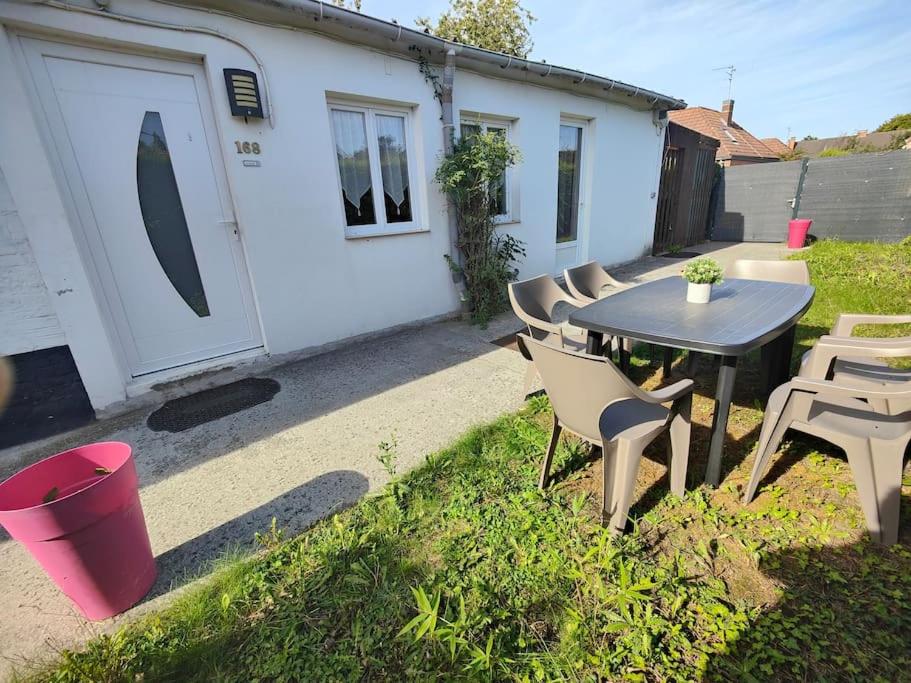 eine Terrasse mit einem Tisch und Stühlen sowie ein Gebäude in der Unterkunft Gîte l'hirondelle in Flers-lez-Lille