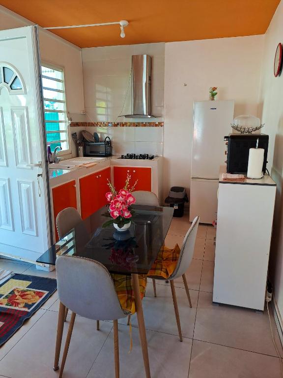 a kitchen with a table and chairs and a refrigerator at Maison d&#39;une chambre avec piscine partagee terrasse amenagee et wifi a Petit Bourg in Petit-Bourg