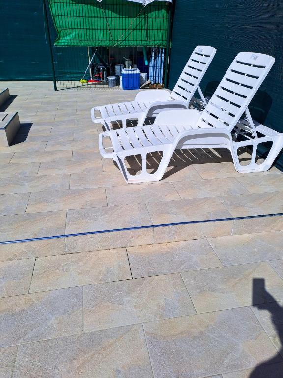 two white lawn chairs sitting on a patio at Maison d&#39;une chambre avec piscine partagee terrasse amenagee et wifi a Petit Bourg in Petit-Bourg