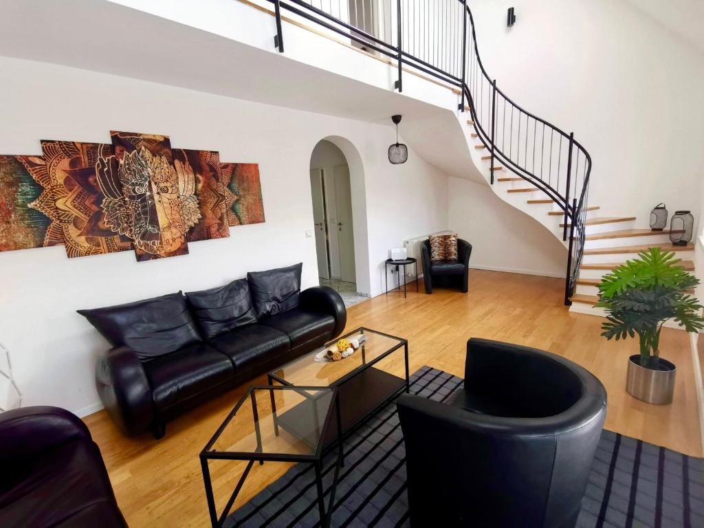 ein Wohnzimmer mit einem schwarzen Ledersofa und einer Treppe in der Unterkunft Vienna Roof Top Apartment with Terrace, Parking and AC in Wien