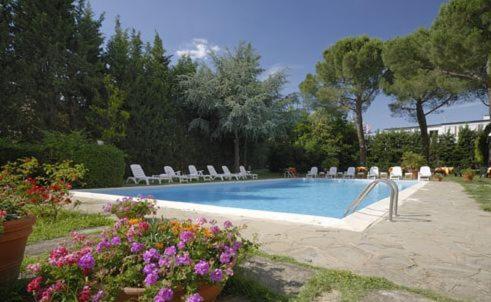 una piscina con sillas y flores en un patio en Hotel First, en Calenzano