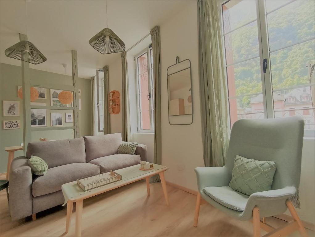 een woonkamer met een bank, een tafel en een stoel bij Le Cocon du Lisey, le joyau du vieux Cauterets in Cauterets