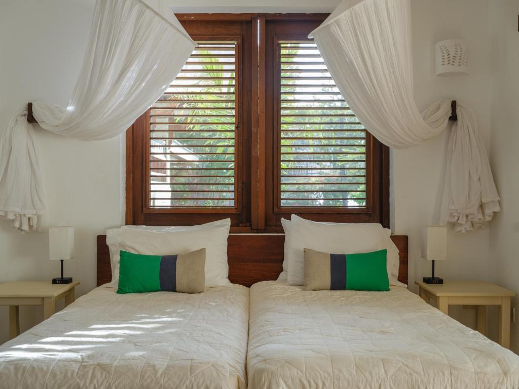 two beds in a bedroom with two windows at Gingerbread Suites in Port Elizabeth