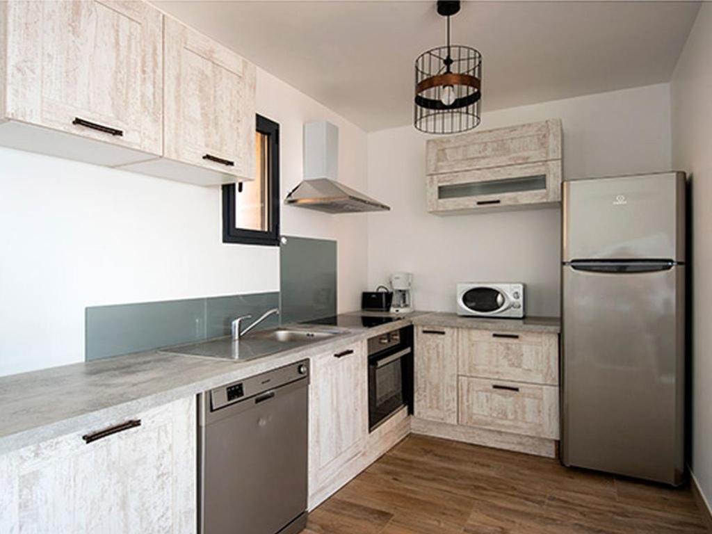 cocina con armarios de madera y nevera de acero inoxidable en Apartment T3 premium vue mer by Interhome, en Zonza