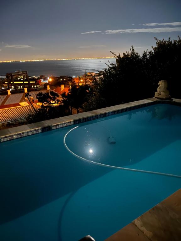 a swimming pool with a view of the ocean at night at Behrs Lair Luxury Villa Simons Town in Cape Town