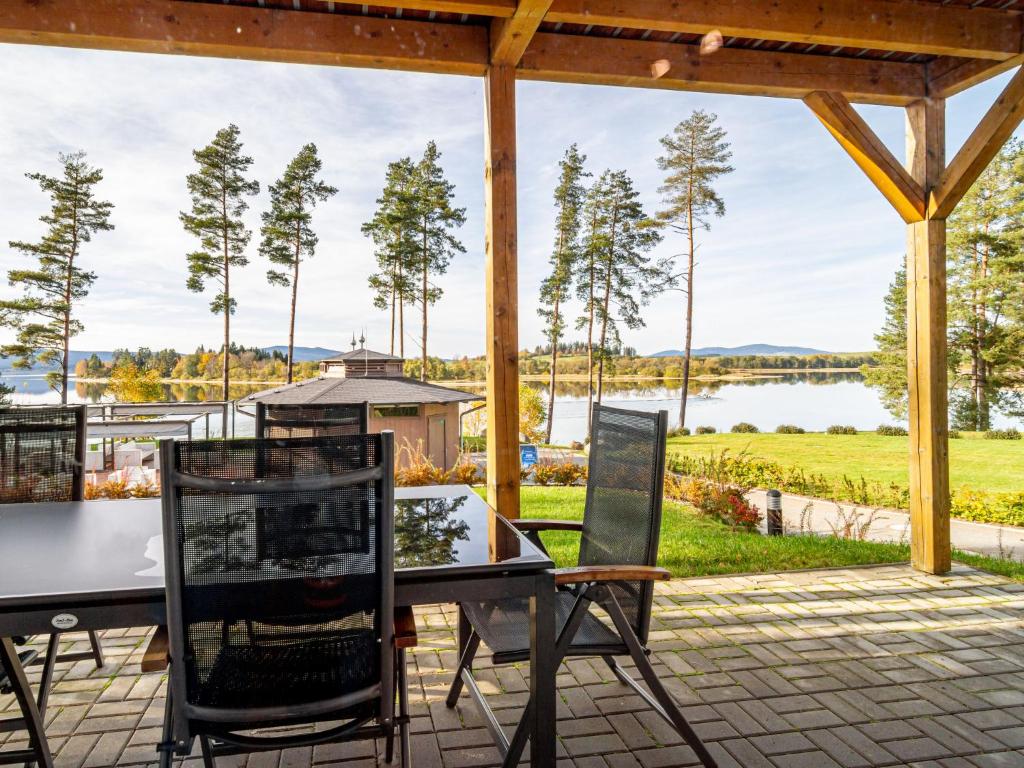 a patio with a table and chairs and a view of a lake at Holiday Home Lakeside Village 18 - - sauna by Interhome in Frymburk