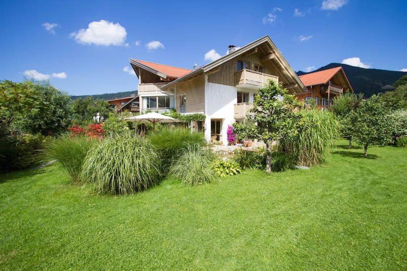 une grande maison avec une cour recouverte d'herbe dans l'établissement Ferienwohnung Martina Bauer, à Oberammergau