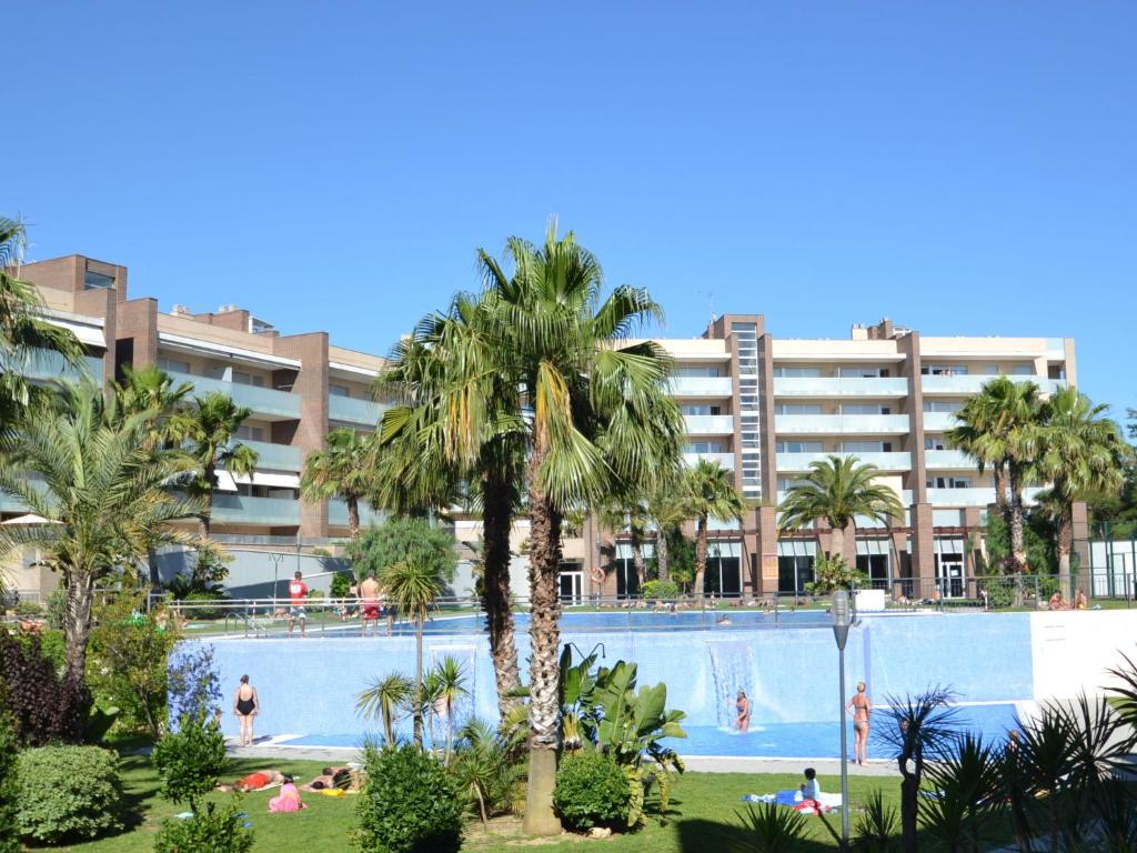a swimming pool with palm trees and a large building at Apartment Aquaria-5 by Interhome in Salou