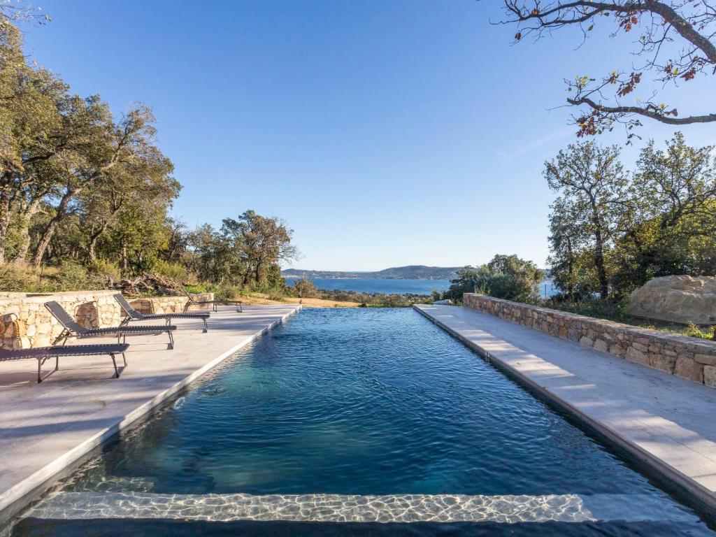 un bassin d'eau avec deux bancs à côté dans l'établissement Holiday Home Le Mas du Golfe by Interhome, à Grimaud