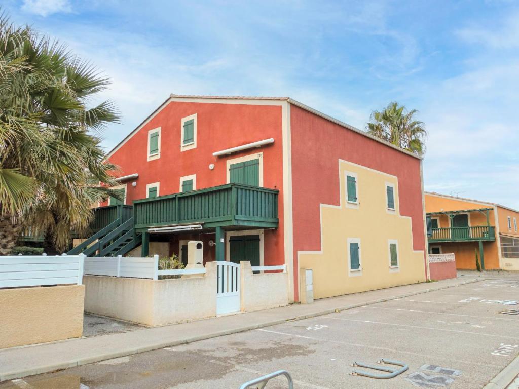 a red building with palm trees next to a parking lot at Apartment Eden Roc 2 by Interhome in Narbonne-Plage