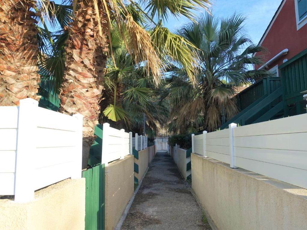 a fence with palm trees in the background at Apartment Eden Roc 2 by Interhome in Narbonne-Plage