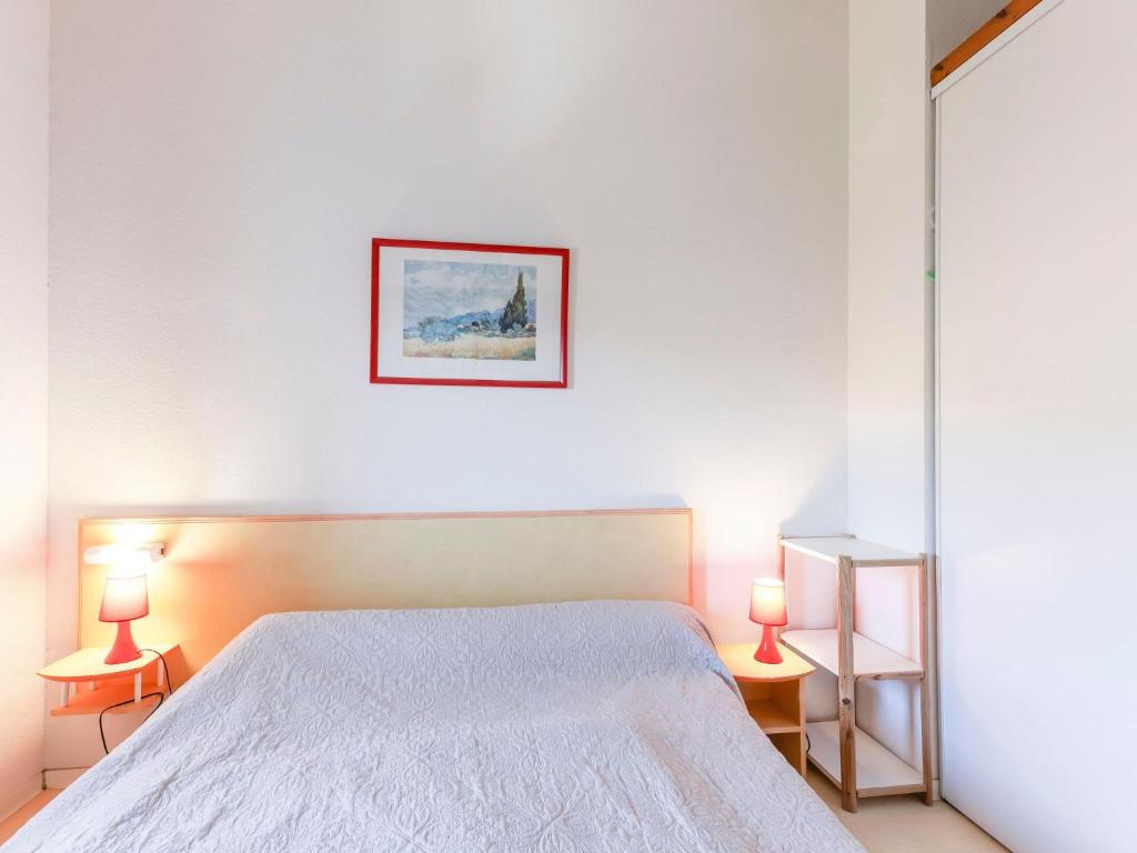 a white bedroom with a bed and two lamps at Apartment Eden Roc 2 by Interhome in Narbonne-Plage
