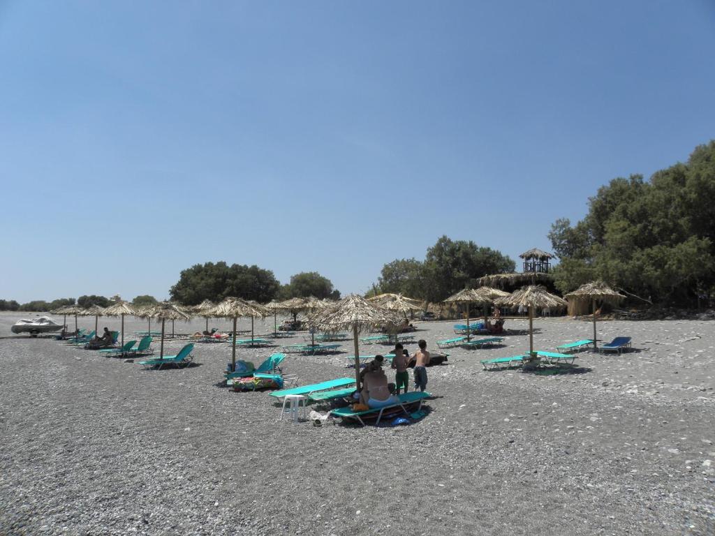 a group of people sitting on a beach with umbrellas at Megim Hotel in Palaiochora