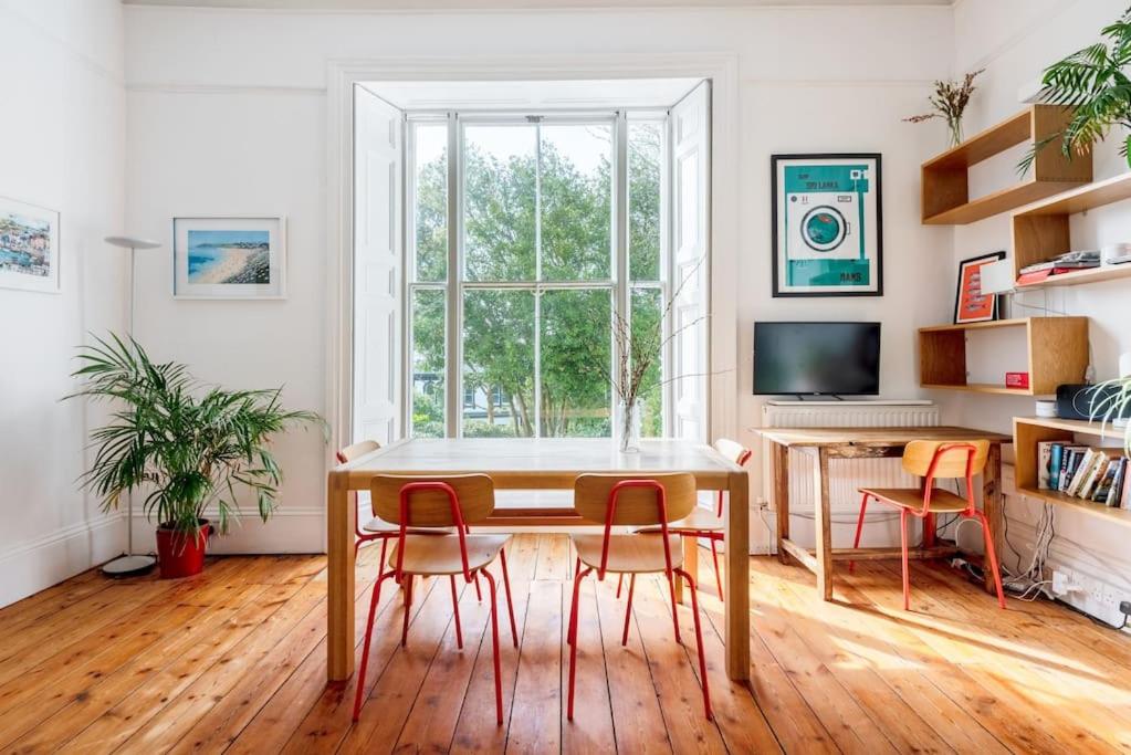 a dining room with a table and four chairs at Treetops - Characterful flat with parking, close to beach in Falmouth