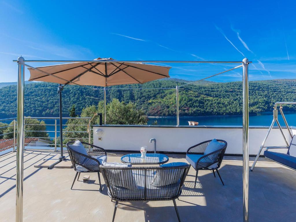 une terrasse avec une table, des chaises et un parasol dans l'établissement Holiday Home Villa Dragica by Interhome, à Labin