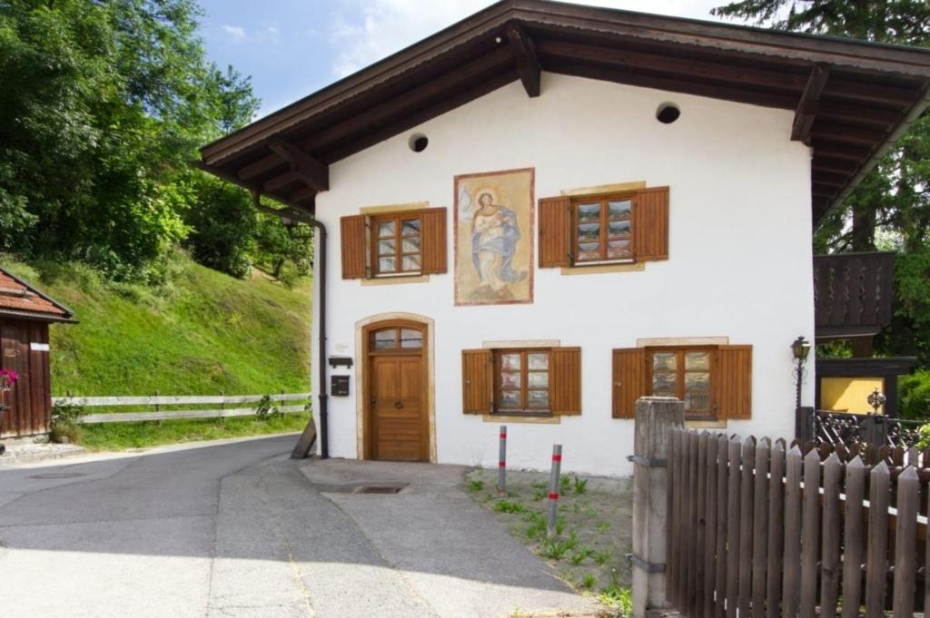 Casa blanca pequeña con ventanas de madera y valla en Hölzlhaus - a74066, en Mittenwald