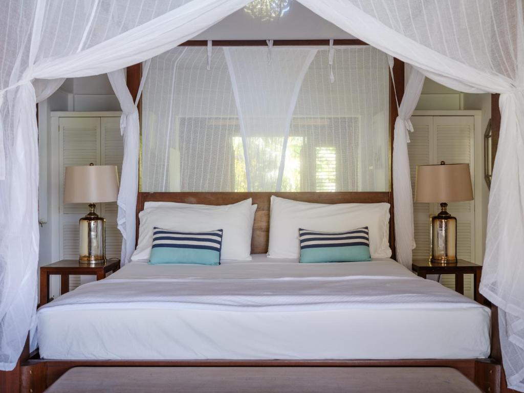 a bedroom with a white canopy bed with blue pillows at Gingerbread Suites in Port Elizabeth