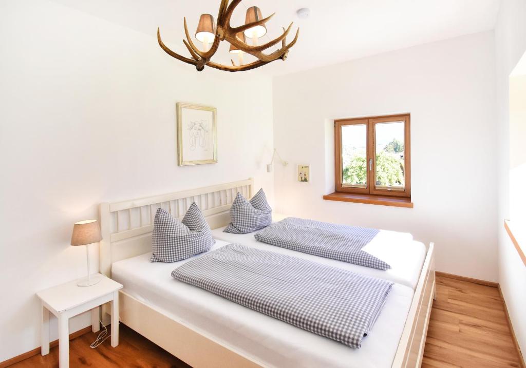 two beds in a white room with a chandelier at Vogelmann Suite in Pfronten