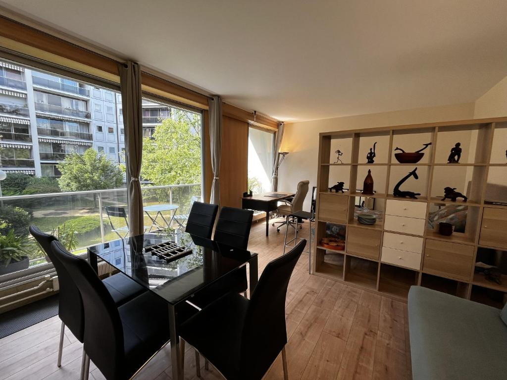 une salle à manger avec une table, des chaises et une grande fenêtre dans l'établissement Spacieux studio sur jardin, beaucoup de charme, à Boulogne-Billancourt