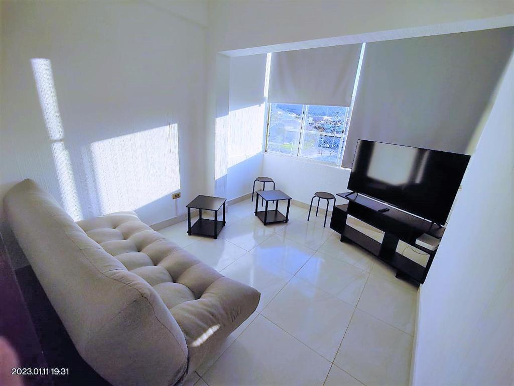 ein Wohnzimmer mit einem Sofa und einem Flachbild-TV in der Unterkunft La mejor ubicación de Arica in Arica