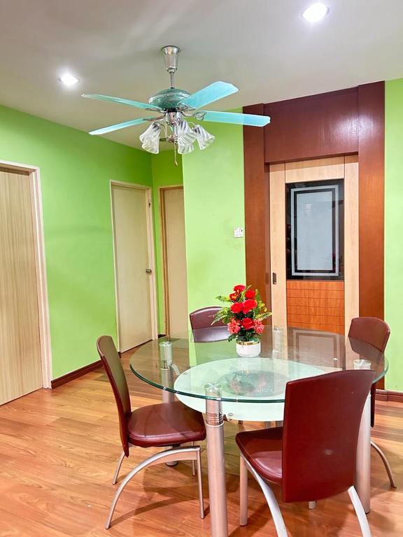 a dining room with a glass table and a ceiling fan at BC Homestay in Sandakan