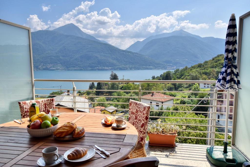 a table on a balcony with a view of the mountains at Bello Pianello Lake View Apartment in Pianello Del Lario