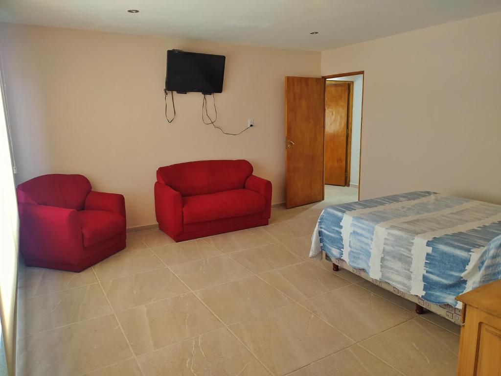 1 dormitorio con 2 sillas rojas, 1 cama y TV en Simplicity Apart en San Rafael
