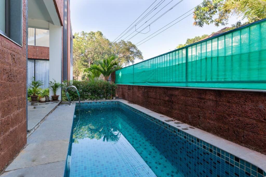 オールド･ゴアにあるLuxury 3BHK Villa with Private Pool near Anjunaのレンガの壁と建物の隣にスイミングプール