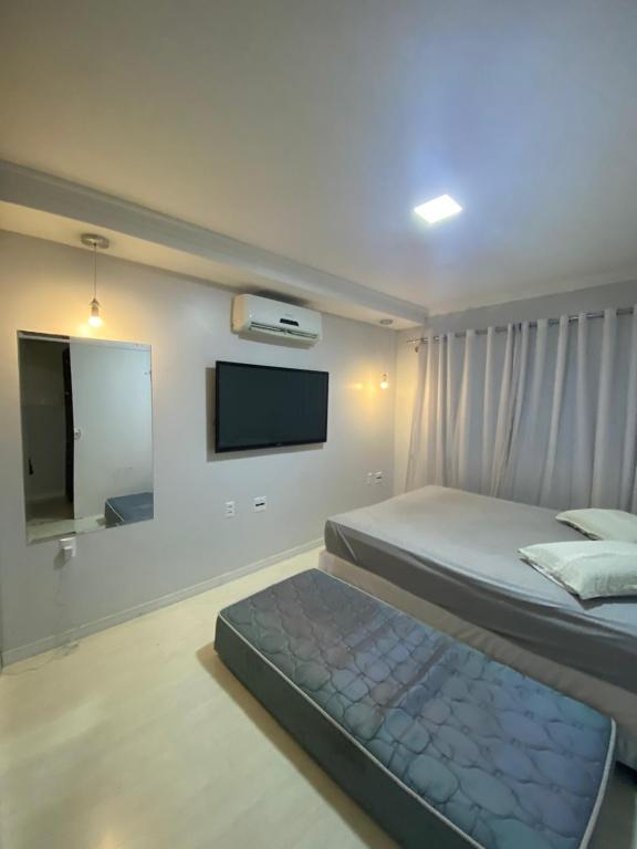 a bedroom with a bed and a flat screen tv at Casa Temporada in Camboriú