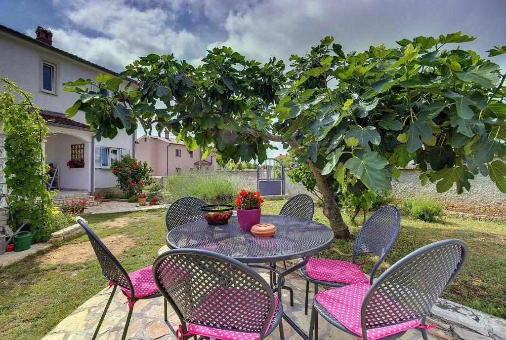 a patio table and chairs with a tree at Appartement Tiffany in Ližnjan