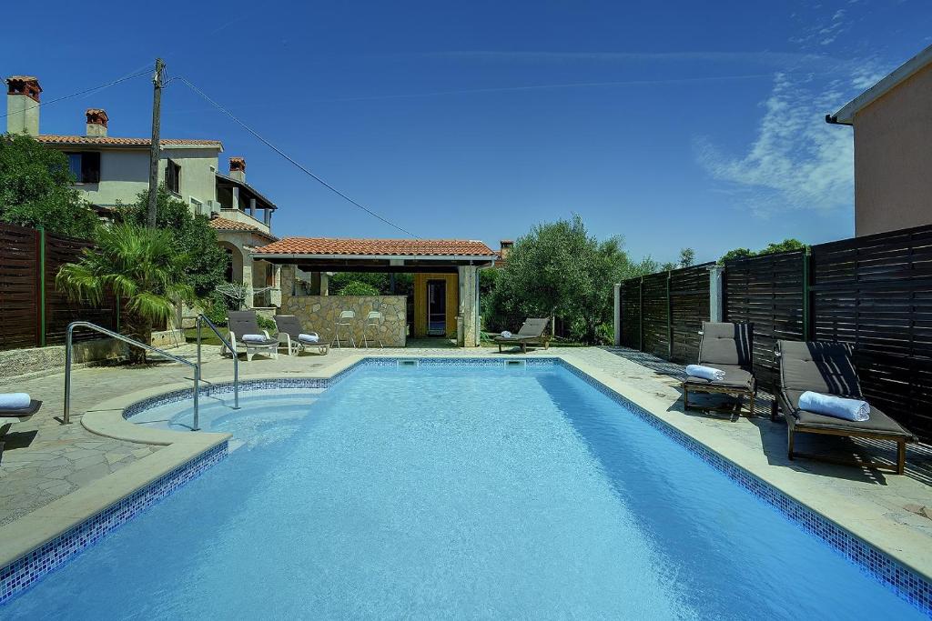 a swimming pool with two chairs and a house at Einzigartige Villa nur 1 km bis zum Strand mit privatem Pool, BBQ, Klima, WLAN in Ližnjan