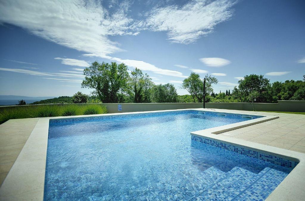 een zwembad met blauw water in een tuin bij Schöne Finca mit privatem Pool, Klima, WLAN, Terrasse, Grill in Kavran