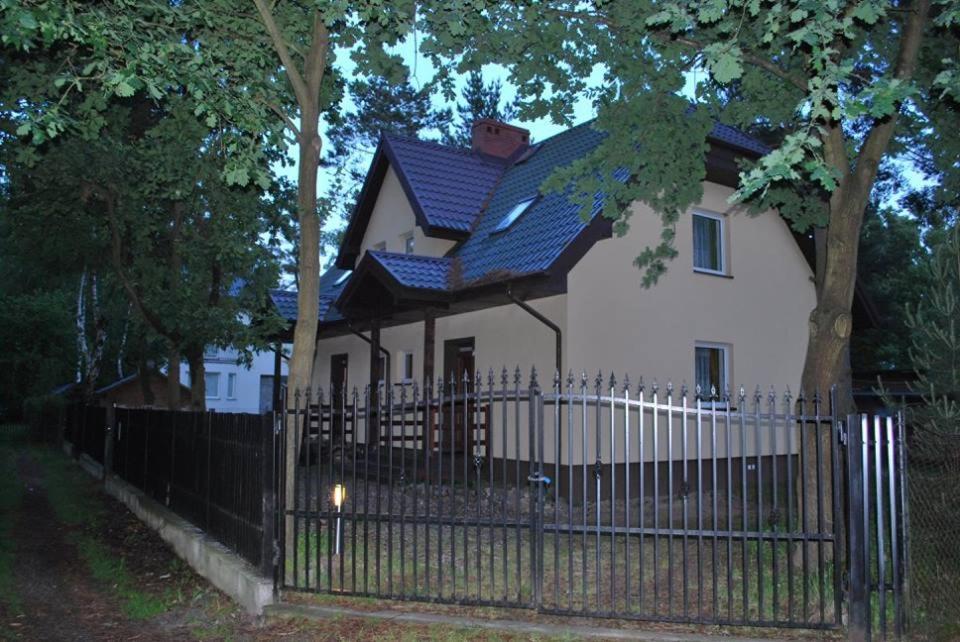 a white house behind a fence with a blue roof at Domimat-Lila in Dębki