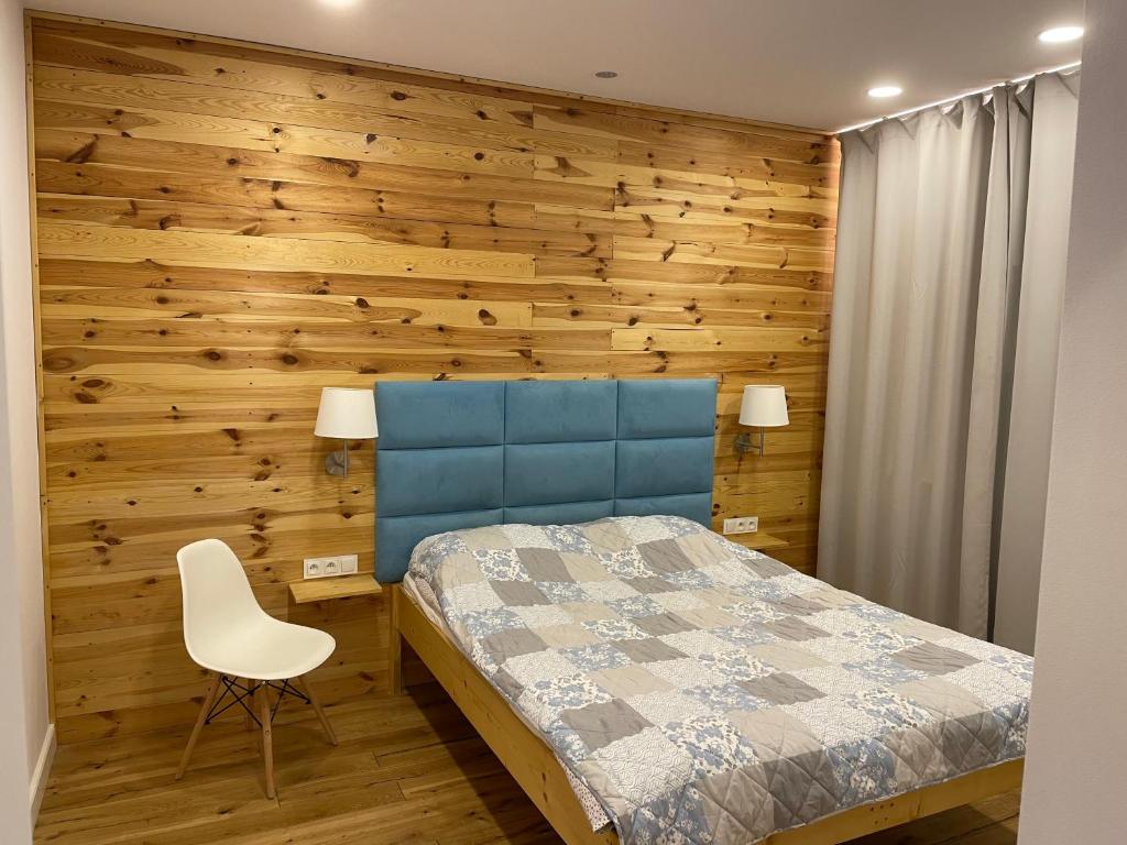 1 dormitorio con pared de madera, cama y silla en Willa BROWAR pokoje gościnne en Starogard Gdański