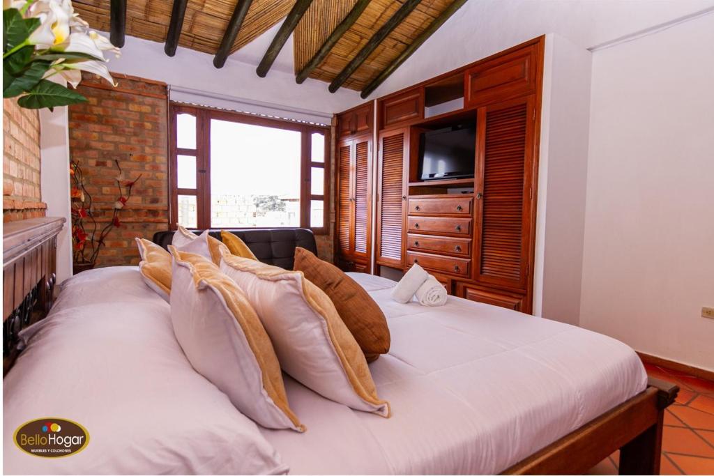 a bedroom with a large bed with a television on it at Bello Hogar Hospedaría VDL in Villa de Leyva