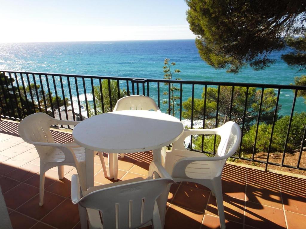 una mesa blanca y sillas en un balcón con vistas al océano en Bertur Cala Llevado en Tossa de Mar