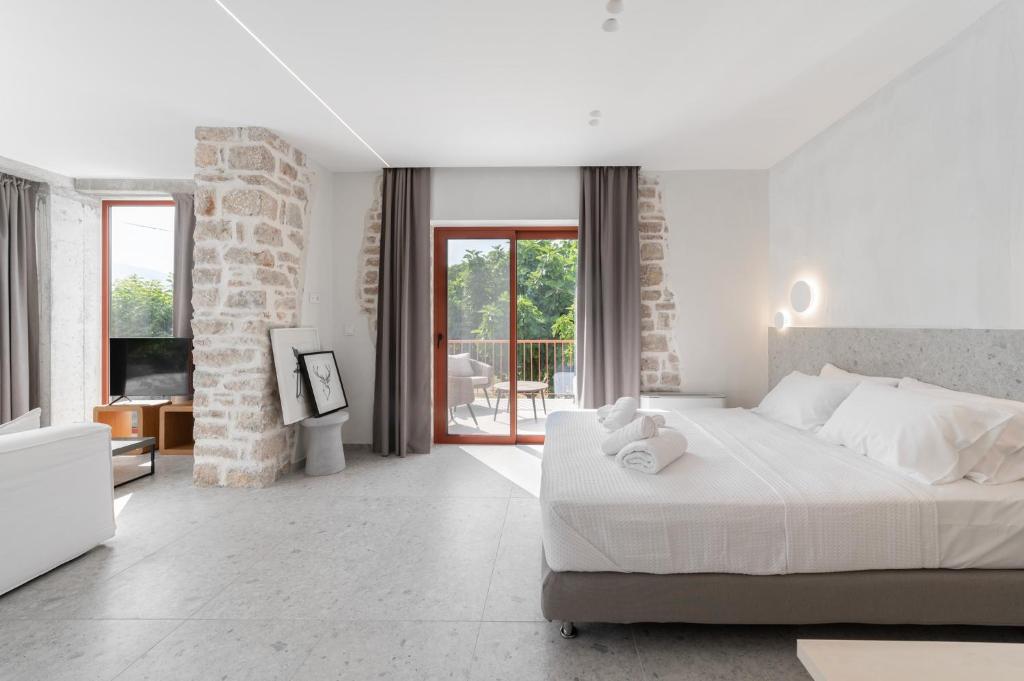 Un dormitorio blanco con una cama grande y un balcón. en Kampus Luxury Villas, en Tríkala