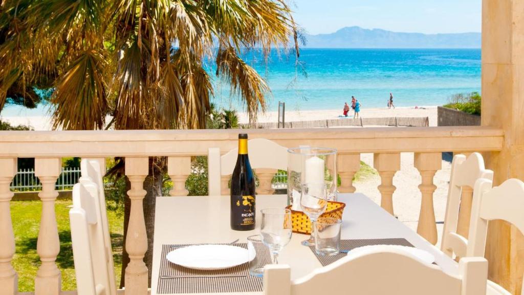 uma mesa com uma garrafa de vinho numa varanda com praia em SUN OF THE BAY em Alcudia