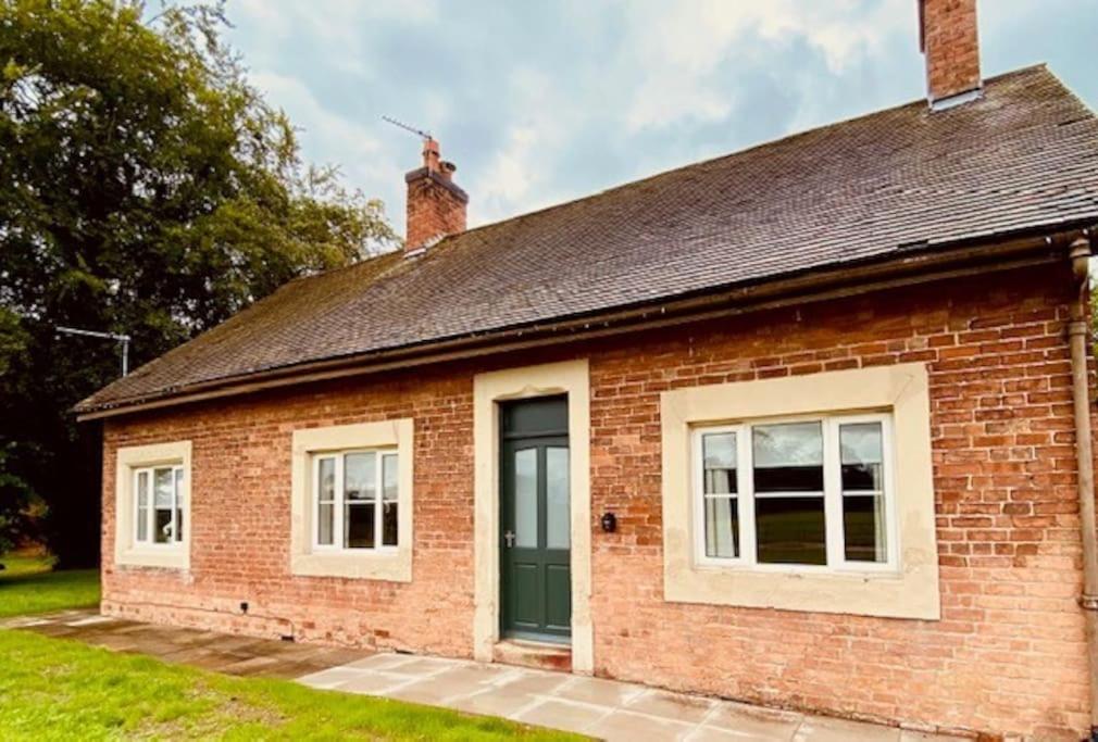 a brick house with a green door and windows at Cosy Bungalow with a view in Lincoln