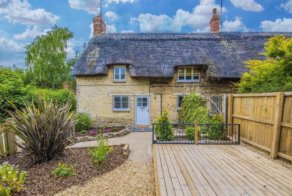 a cottage with a wooden walkway in front of it at Blackbird Cottage in Kettering