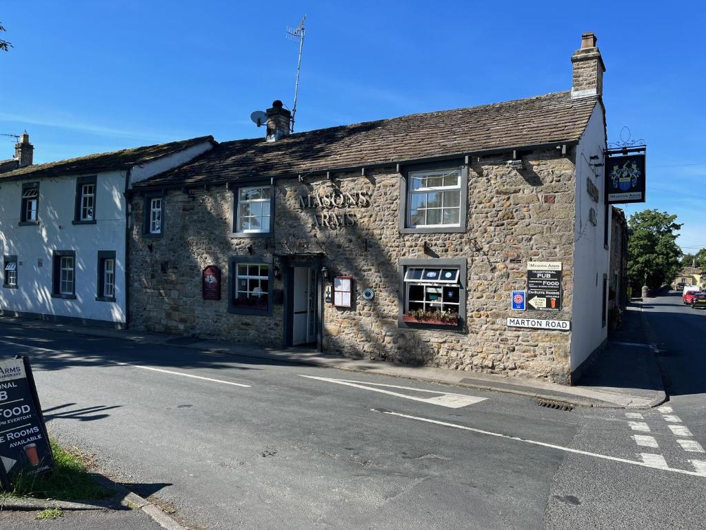 um edifício de pedra ao lado de uma rua em Masons Arms em Skipton