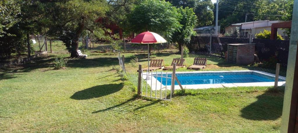 a backyard with a swimming pool with an umbrella and chairs at Cabaña La Calandria in San José del Rincón